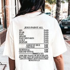 the back of a person wearing a white shirt with black writing on it that says jesus paid all our shame