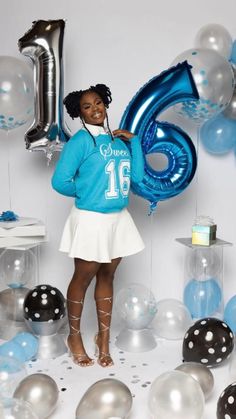 a woman standing in front of balloons with the number six on her shirt and skirt