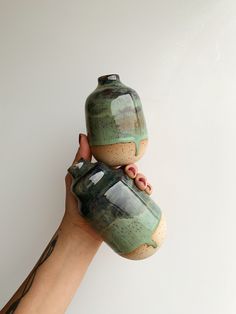 a hand holding a green and brown vase