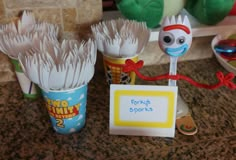 two plastic spoons with toothbrushes in them sitting on a counter next to other toys