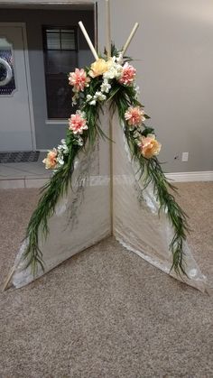 an arrangement of flowers and greenery is placed in the corner of a room on the floor