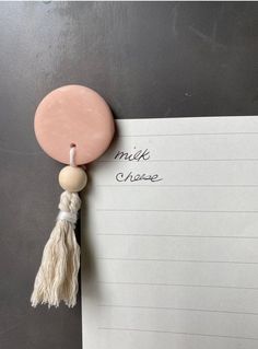 a note with a tassel hanging from it's side next to a piece of paper