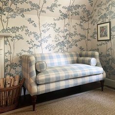 a blue and white checkered couch sitting in front of a wall with trees on it