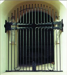 an iron gate with bars on the top and bottom is open in front of a doorway