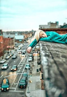 a woman laying on top of a wooden roof next to traffic