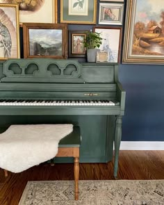 a green piano sitting on top of a hard wood floor next to pictures and paintings