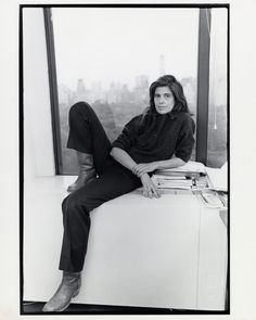 a woman sitting on top of a window sill in front of a cityscape