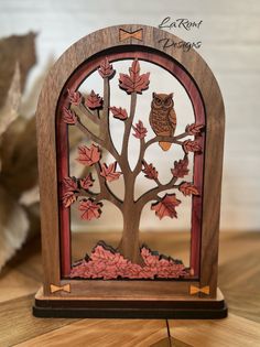 an owl sitting on top of a tree in front of a wooden frame with leaves