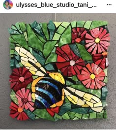 a glass mosaic with flowers and a bee on it