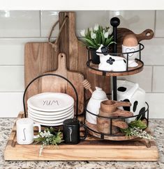 a wooden cutting board topped with plates and bowls on top of a counter next to utensils