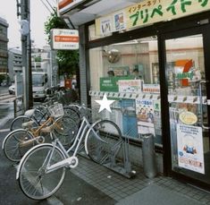 there are many bicycles parked in front of the storefront and on the sidewalk next to the street