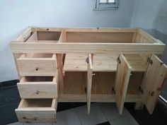 an unfinished wooden cabinet with drawers on the bottom