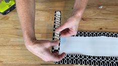 a person is making a paper chain on a piece of construction material that has been taped to the floor