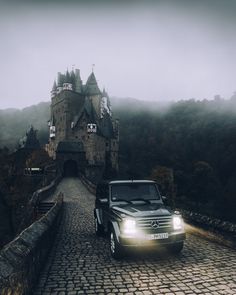 a car driving down a cobblestone road in front of a castle