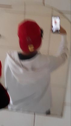 a man in white shirt and red hat taking a selfie