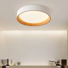 a modern living room with white walls and wood accents on the ceiling is lit by a circular light fixture