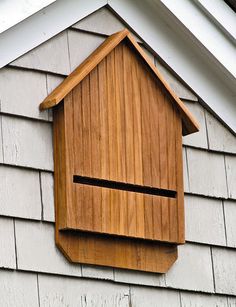 a wooden birdhouse hanging on the side of a house