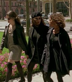 three women are walking down the sidewalk together