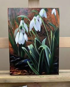 a painting of snowdrops on a wooden shelf in front of a gray wall