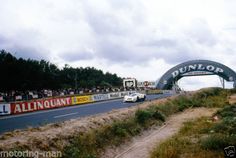 a race track with cars going under an arch and people watching from the sidelines