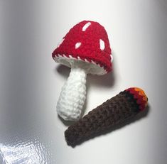 two crocheted mushrooms are sitting next to each other on a white table top