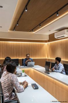 three people sitting at a table with laptops