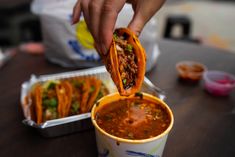 a person holding a tortilla in their hand and dipping it into a cup