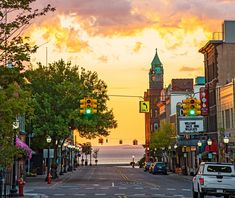 a city street at sunset with traffic lights and buildings on both sides, cars driving down the road