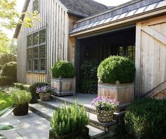 a wooden house with potted plants in the front yard