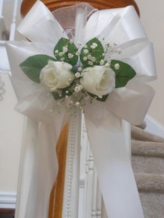 a white rose and baby's breath ribbon tied to a banister