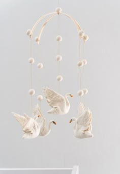 three white birds hanging from a mobile with balls