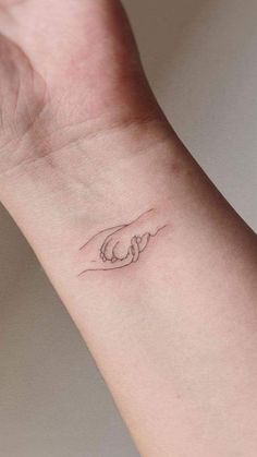 a small hand with a wave tattoo on the wrist