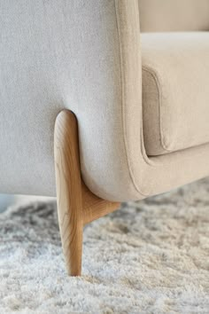 a close up view of the arm and back of a modern chair with wood legs