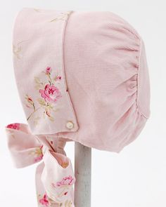 a pink hat with flowers on it sitting on top of a pole