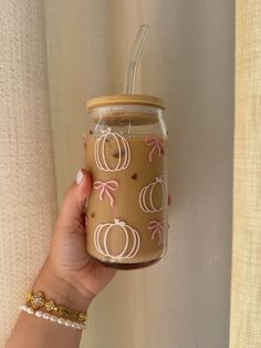 a hand holding a glass jar with pumpkins painted on it