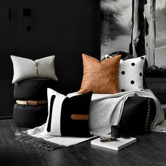 black and white pillows are sitting on the floor in front of a wall with an abstract painting