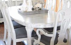 a dining room table with chairs and a tray on top of it in front of a window