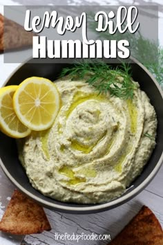 a bowl filled with hummus and lemon wedges