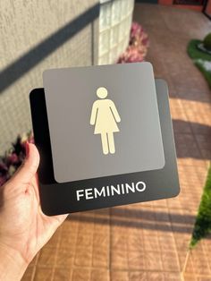 a person is holding up a sign that says feminino in front of a house