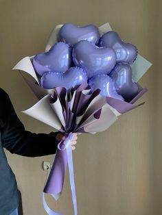 a man holding a bunch of balloons in his hand and tied to the wall behind him