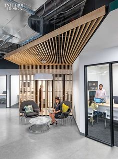 two people are sitting in an office with wooden slats on the ceiling and windows