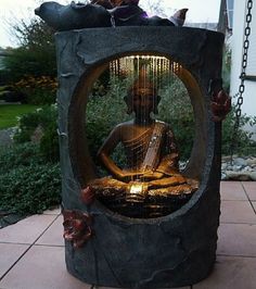 a buddha statue sitting in the middle of a garden with lights on it's sides