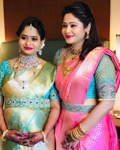 two beautiful women standing next to each other wearing different colored sari and necklaces