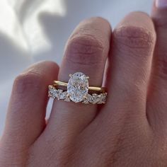 a woman's hand with a diamond ring on top of her finger and the engagement band