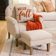 a chair and ottoman in a living room with pillows on the floor, and a pillow that says hello fall