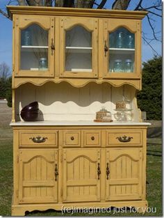 a yellow china cabinet sitting in the grass