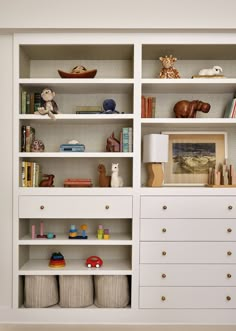 a white bookcase filled with lots of books next to a wall mounted shelf full of toys