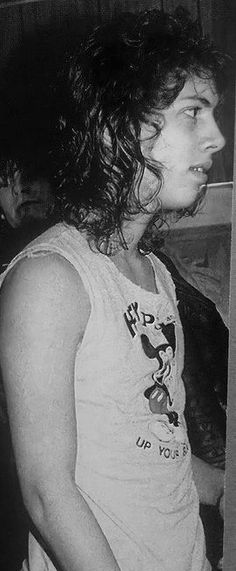 a black and white photo of a man with long hair in a tank top looking off into the distance