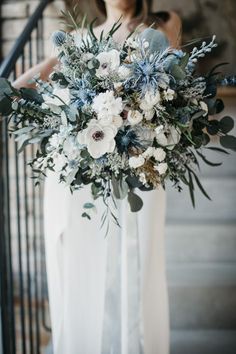 a woman holding a bouquet of flowers on top of a stair case next to a hand rail