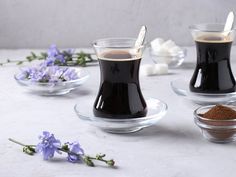 there are three cups with liquid in them on the table next to some lavender flowers